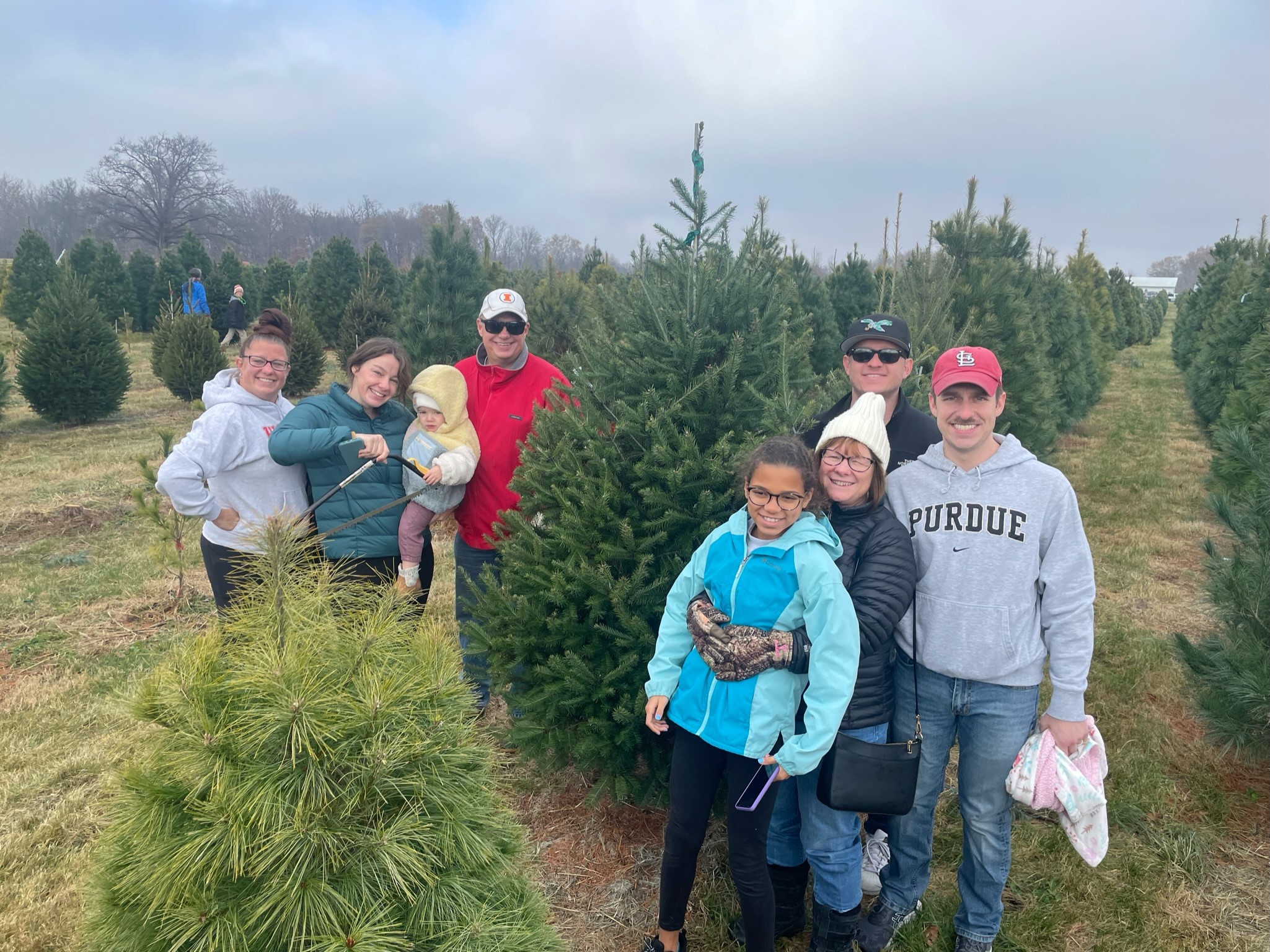 The Bowman family at a Christmas tree farm. Susan has her arms wrapped around her elementary-age granddaughter's waist.