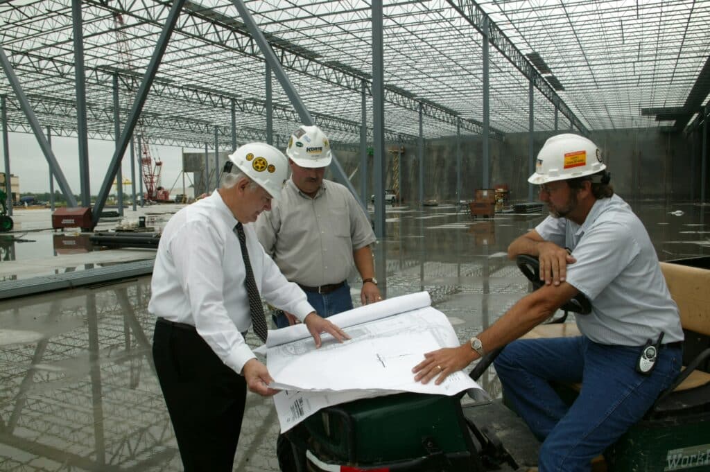 A group of builders and designers discuss project plans on a job site. 